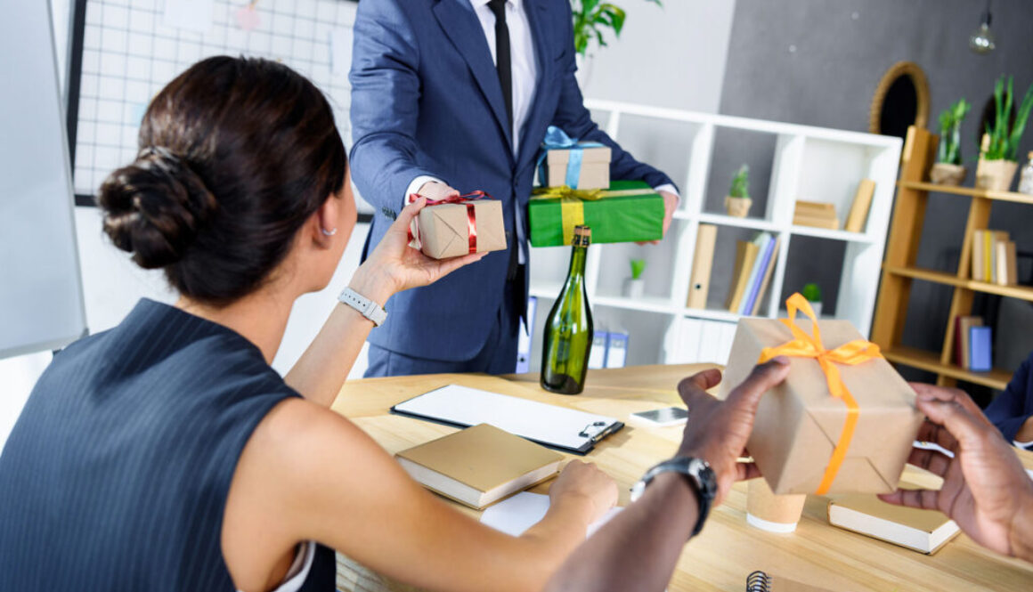 cropped shot of businessman presenting gifts to colleagues in of
